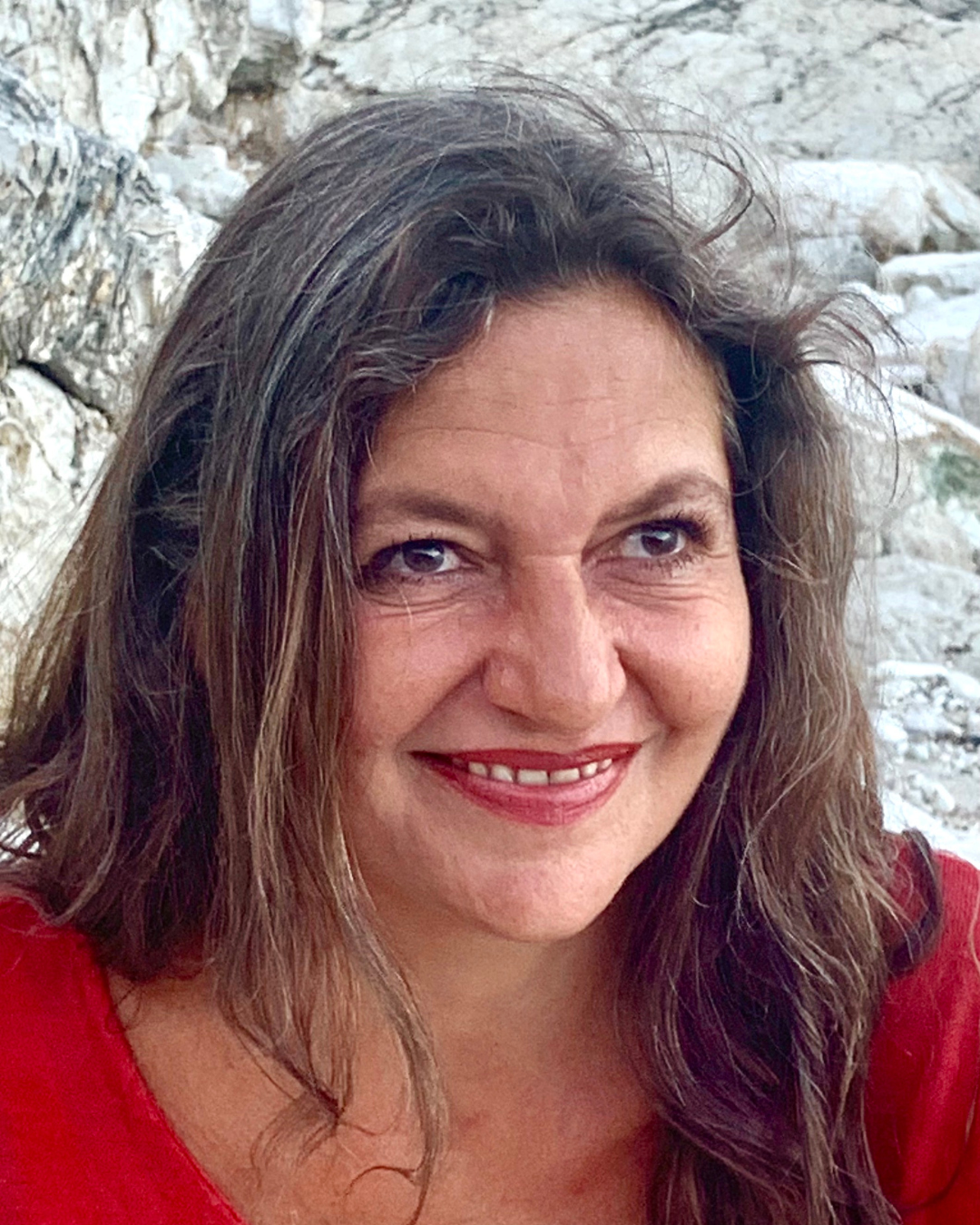 Portrait der Psychotherapeutin Daniela Madjaric, freundlich lächelnd, im Hintergrund natürliche Steinformation